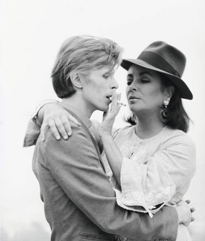 Дэвид Боуи и Элизабет Тейлор, 1975 год. Рассказывает Терри О’Нил: «Лиз попросила меня привести Дэвида к ней домой, в Голливуд, она хотела пригласить его сниматься вместе с ней в фильме («Синяя птица», Ленфильм). Боуи в тот день опоздал почти на три часа, и Тейлор это совсем не понравилось. Я не мог поверить в то, что он заставил себя ждать самую известную в мире кинозвезду. Но она была отходчивой, и я дождался, пока ее гнев уляжется, чтобы сделать эти фотографии».