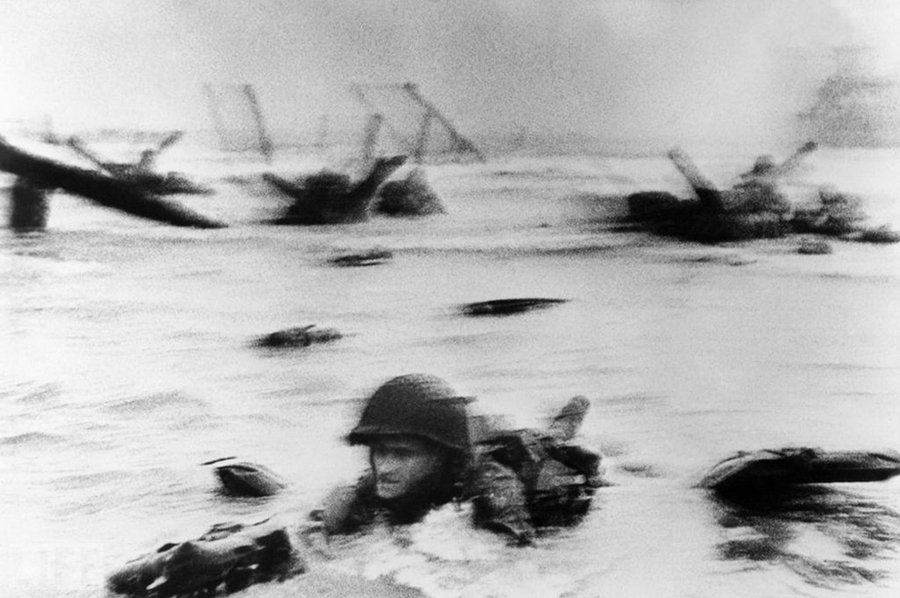 Самый длинный день (The Longest Day). Photo by Robert Capa, 1944.
Момент высадки американской армии на Омаха-бич в Нормандии 6 июня 1944 года, отображенной также в фильме «Спасти рядового Райана» Стивена Спилберга.